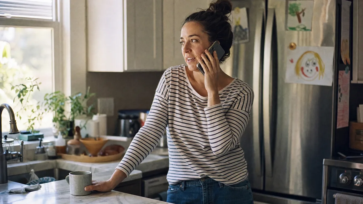 A mother on the phone with the DDE team at her kitchen table.